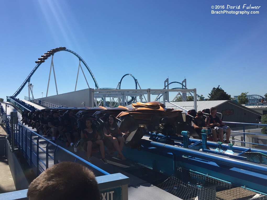 GateKeeper train waits to enter the station on the brakes while another train goes over the hill in the background.  (frame 1 of 2)