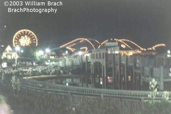 Tidal Force's soaking bridge at night with the Ferris Wheel and Lightning Racer in the background.