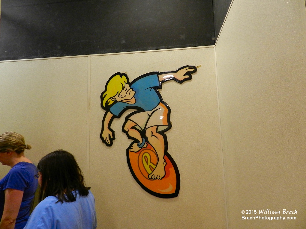 Surfer with a house-arrest monitoring anklet standing on a Reese's Peanut Butter surfboard.