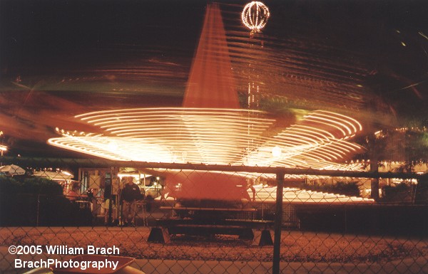 The Barnstormers kiddie airplane ride in motion at night.
