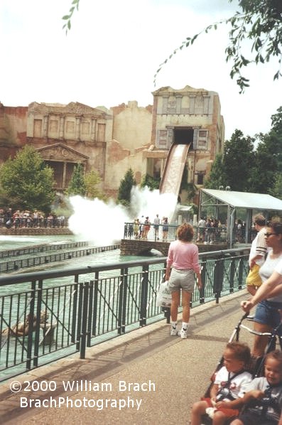 A boat hits the splash pool and pushes water all over the onlookers.