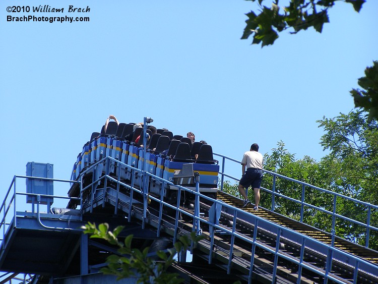 A SooperDooperLooper ride operator is climbign the lift hill stairs to check on the riders and let the know the situation.