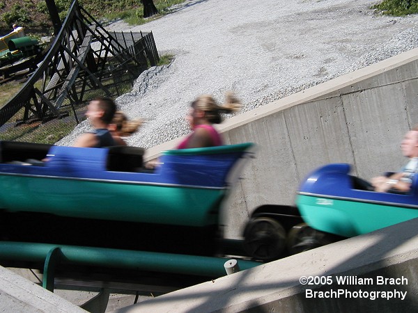 Purple train seen rushing past the queue for Thunderbolt.