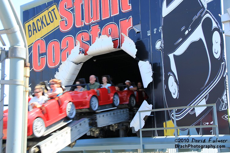 Red train blasting through the billboard to go under the bridge and splash into the riverbed.