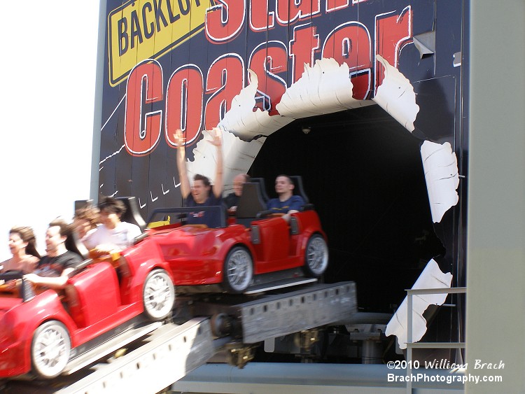 Staff Photographer David Fulmer seen with his hands up in the air as the coaster blasts through the billboard.