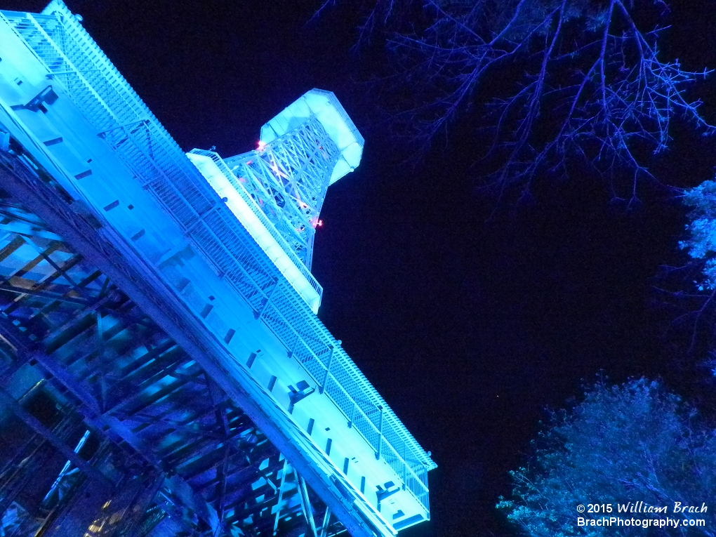 Looking up at the Eiffel Tower glowing in blue lights.