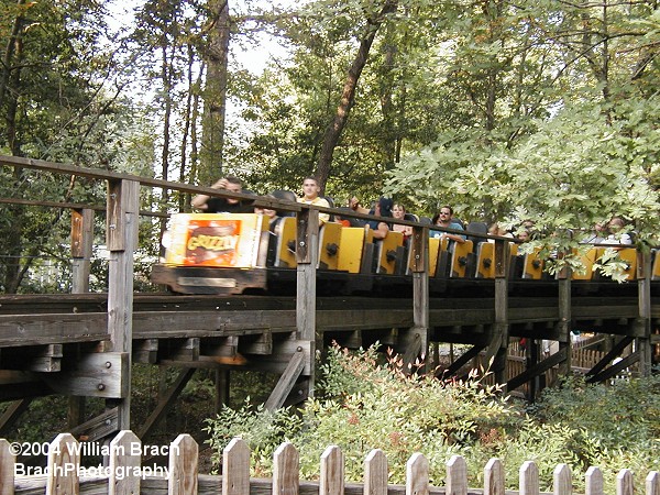 The yellow train has just left the station and is making its way towards the lift hill.