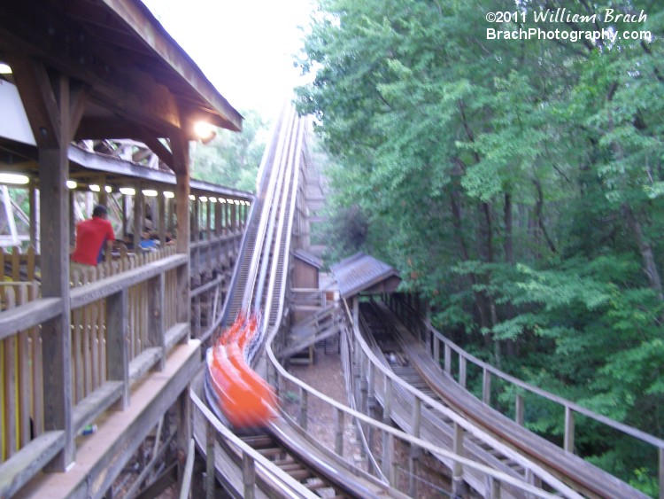 Orange train making its way towards the lift hill.