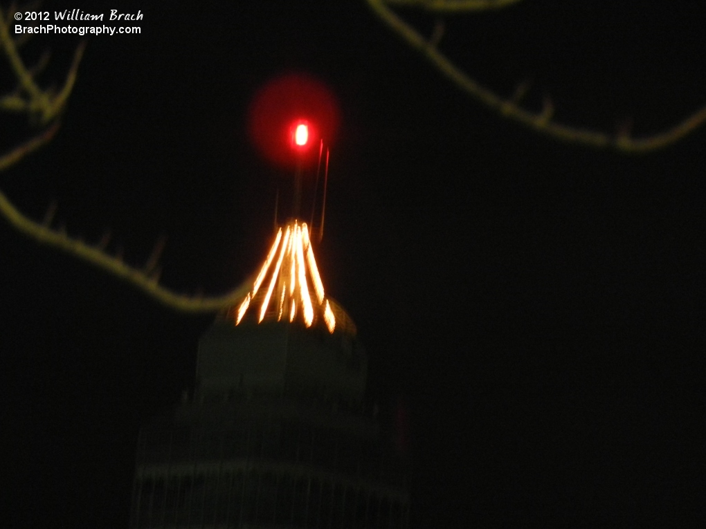 Small Christmas tree atop the Eiffel Tower at night.