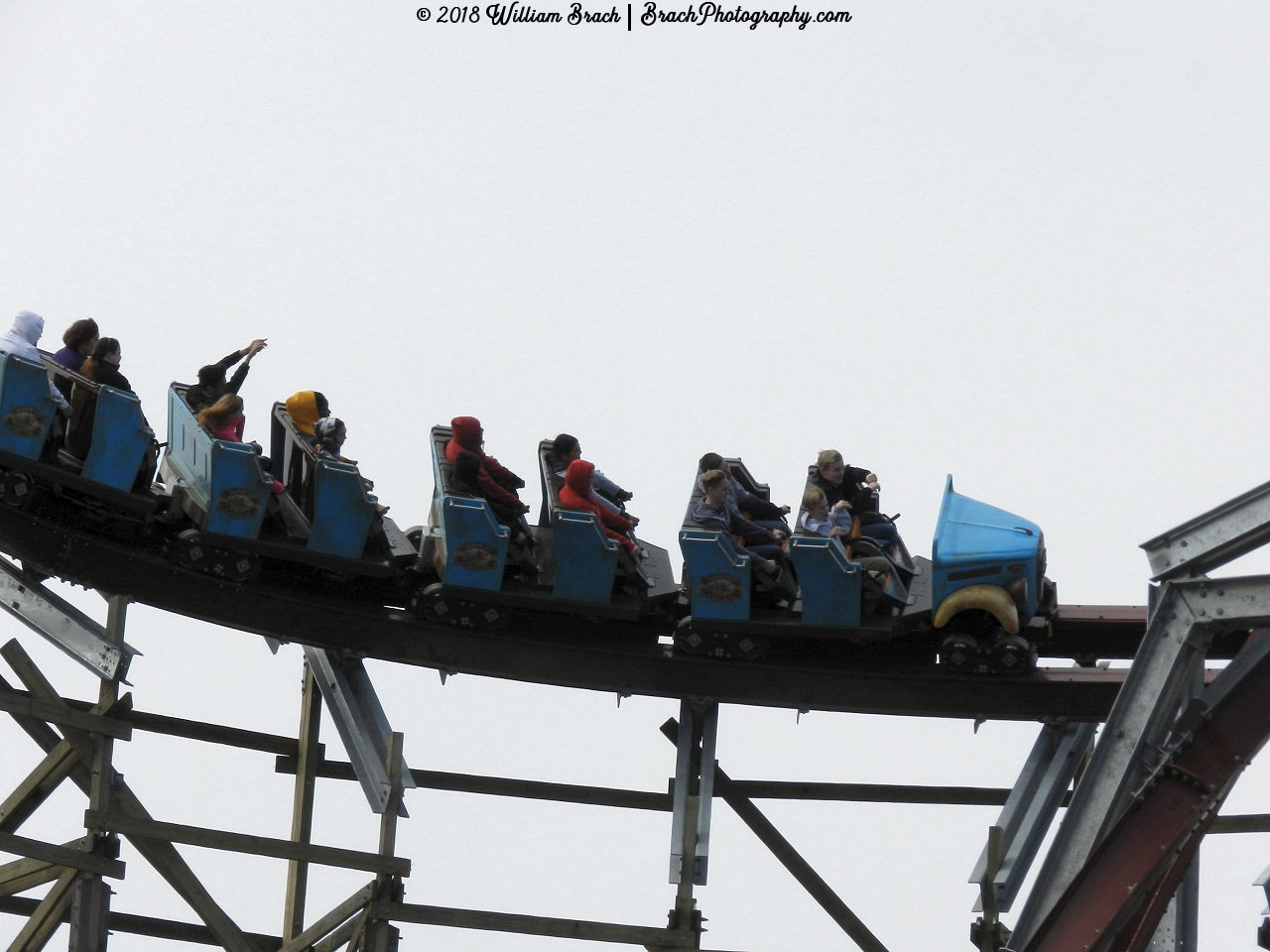 Blue train leaving the lift hill and about to go down the barrel roll drop.