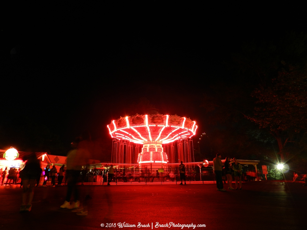 Red lights illuminating the Wave Swinger at night during Halloween Haunt.