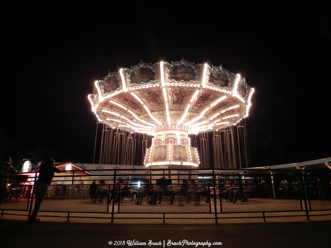 White lights illuminating the Wave Swinger at night during Halloween Haunt.