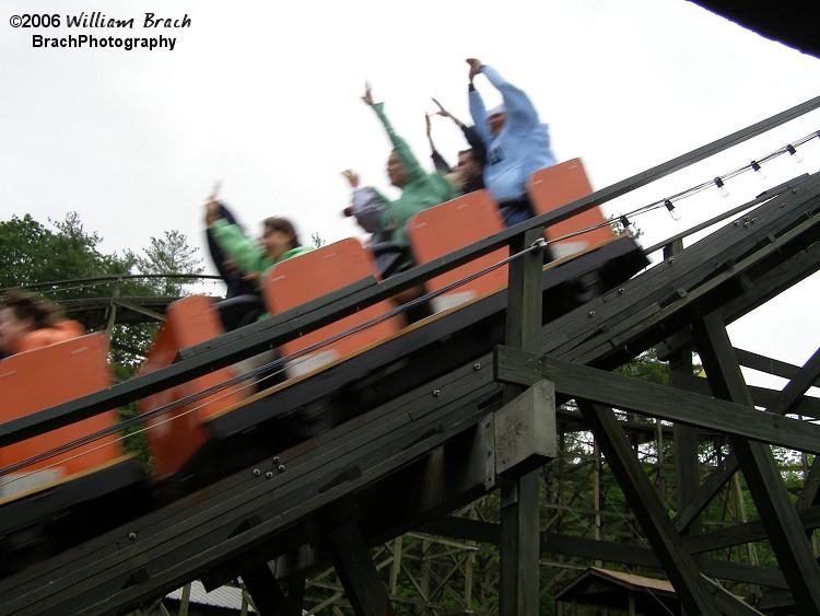 Orange train rushing past the queue area.