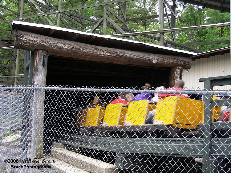 Yellow train entering the tunnel immediately after departing the station.