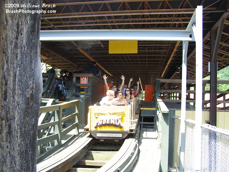 Yellow train rolling out of the station.