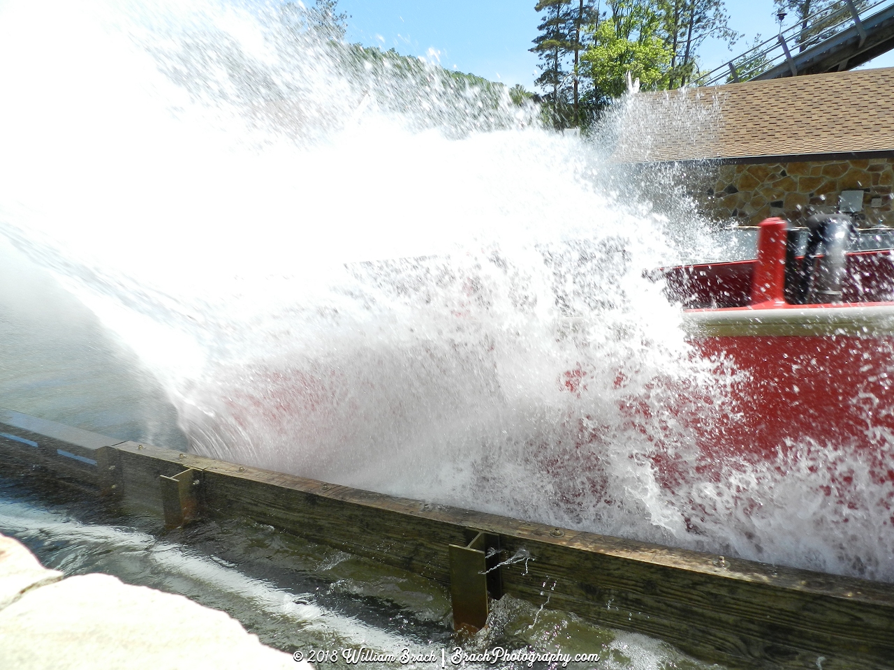 Red boat splashing down into the water pool.