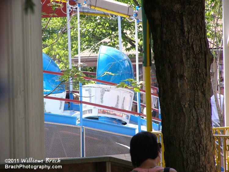 Peeking at the Tilt-A-Whirl from between a tree and a building.