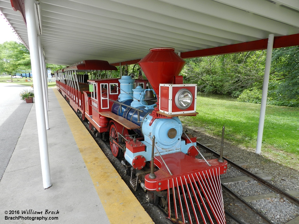 Minature railroad engine sits in the station waiting on the next group of riders.