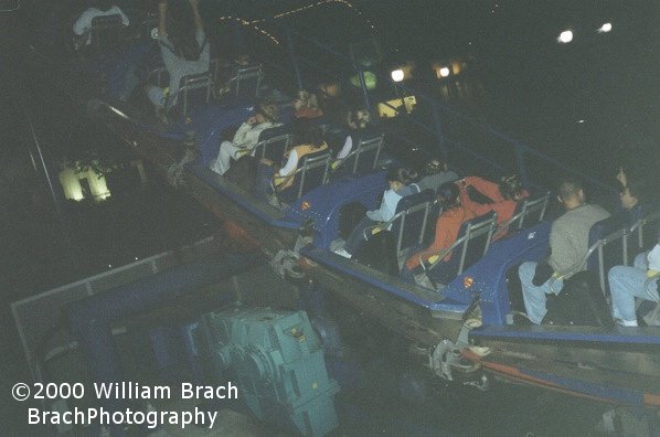 Blue train going up the lift hill at night.