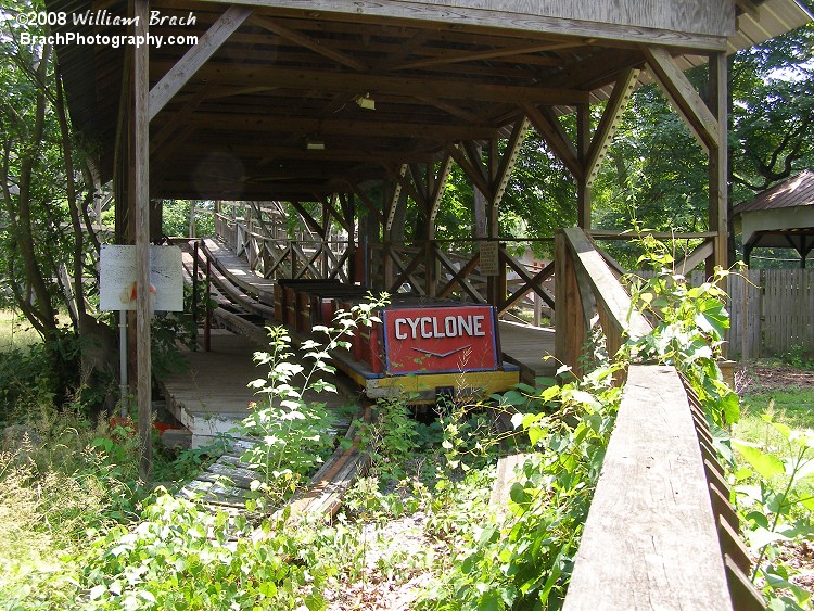 Very sad to see a wooden coaster train parked in the station and blocked in by overgrown plants and weeds.